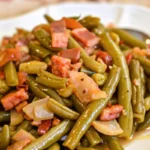 A plate of tender Southern green beans slow-cooked with bacon and onions.