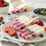 “Homemade Greek yogurt popsicles with berries and honey on a plate – healthy frozen summer treat”