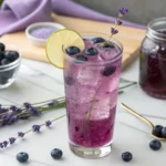Refreshing blueberry lavender fizz mocktail served in a tall glass with ice, lime garnish, and fresh blueberries – non-alcoholic and floral.