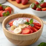 High protein strawberry chia seed pudding in wooden bowl topped with Greek yogurt and fresh fruit