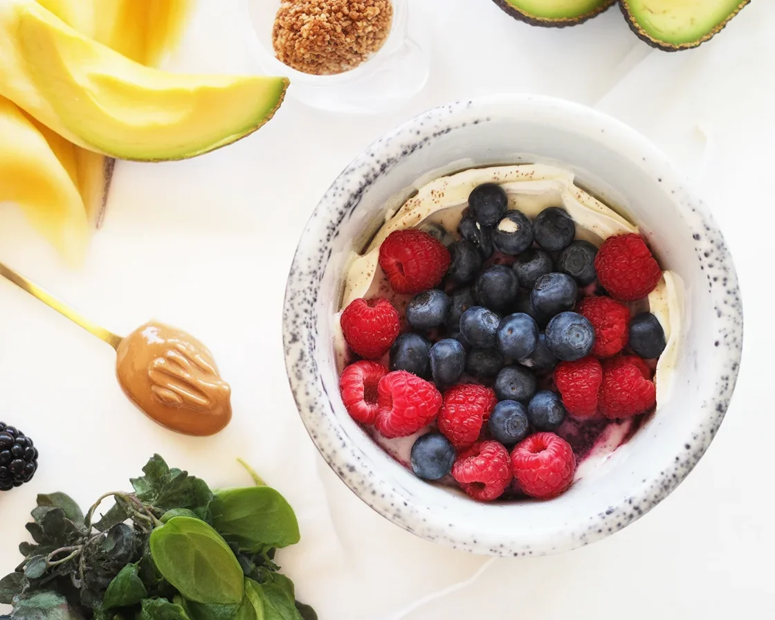 A vibrant green smoothie bowl topped with fruits and seeds, showcasing a healthy meal option.