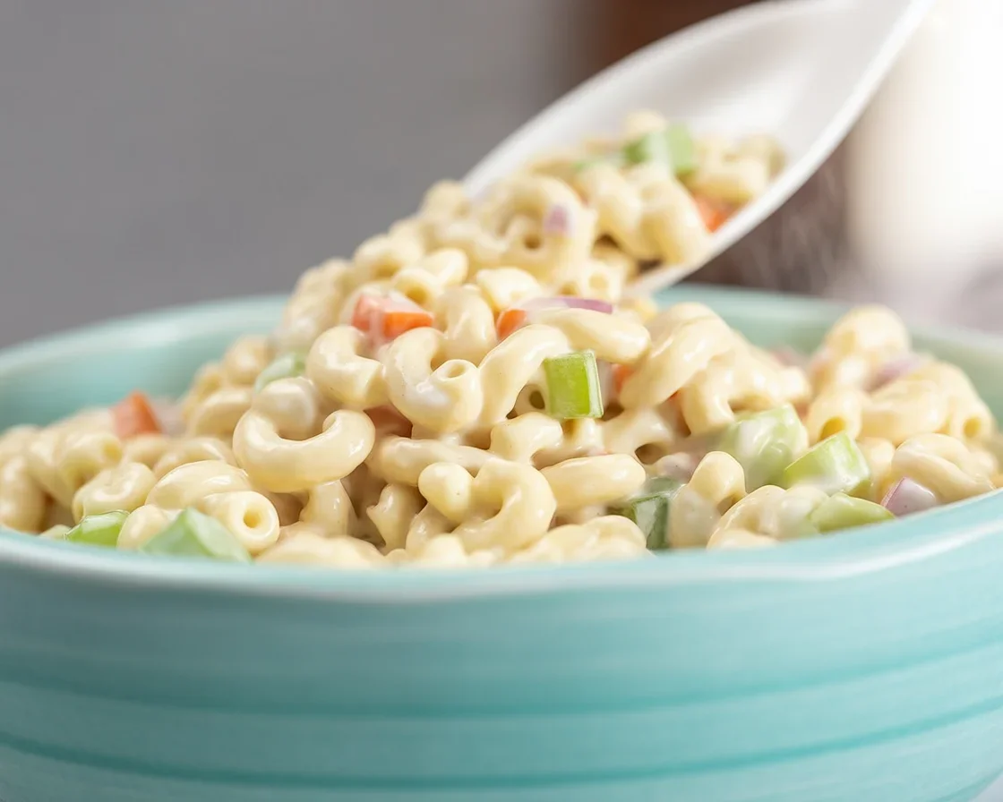 A delicious bowl of creamy macaroni salad with vegetables and dressing.