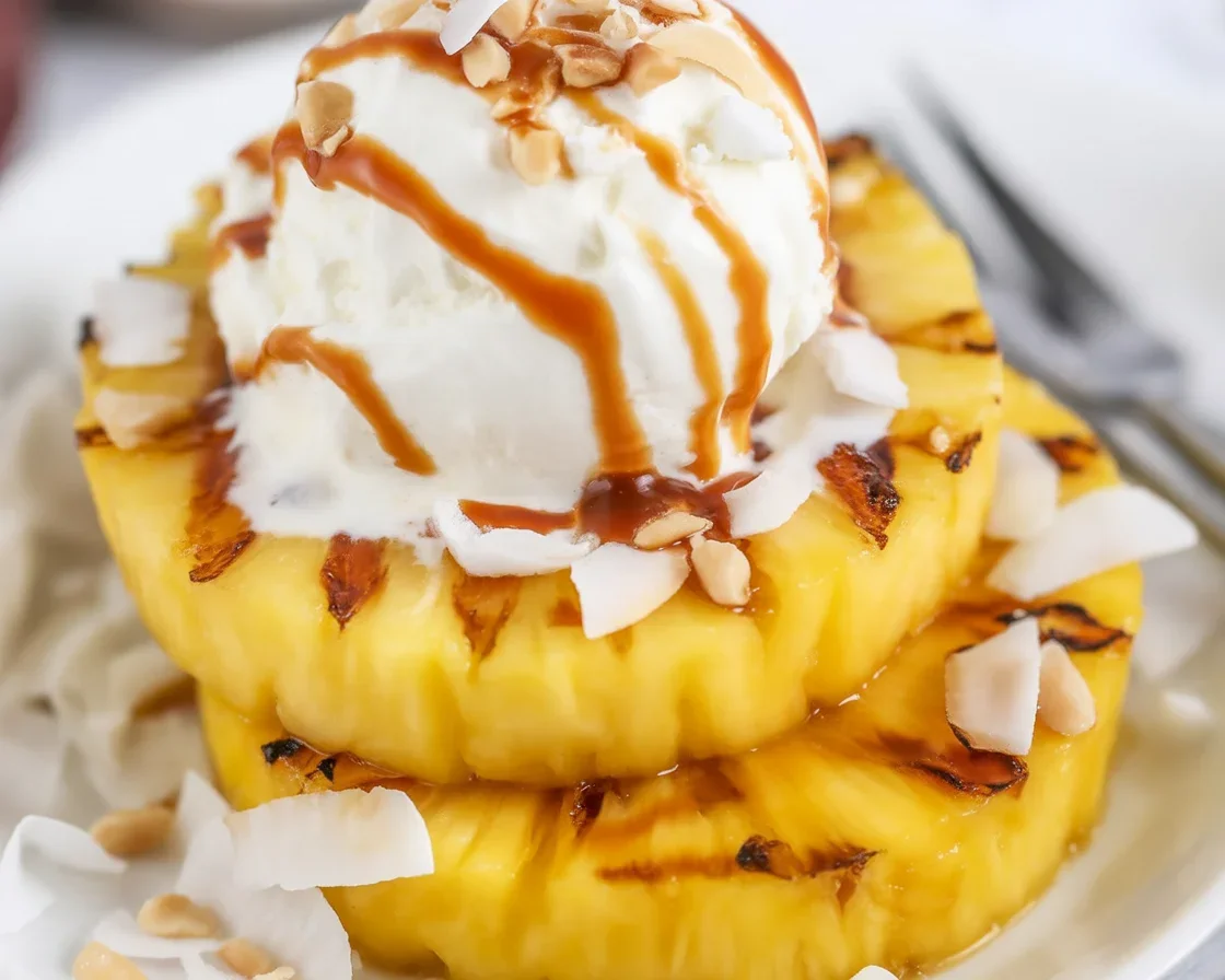 Delicious grilled pineapple topped with creamy coconut ice cream and caramel drizzle.