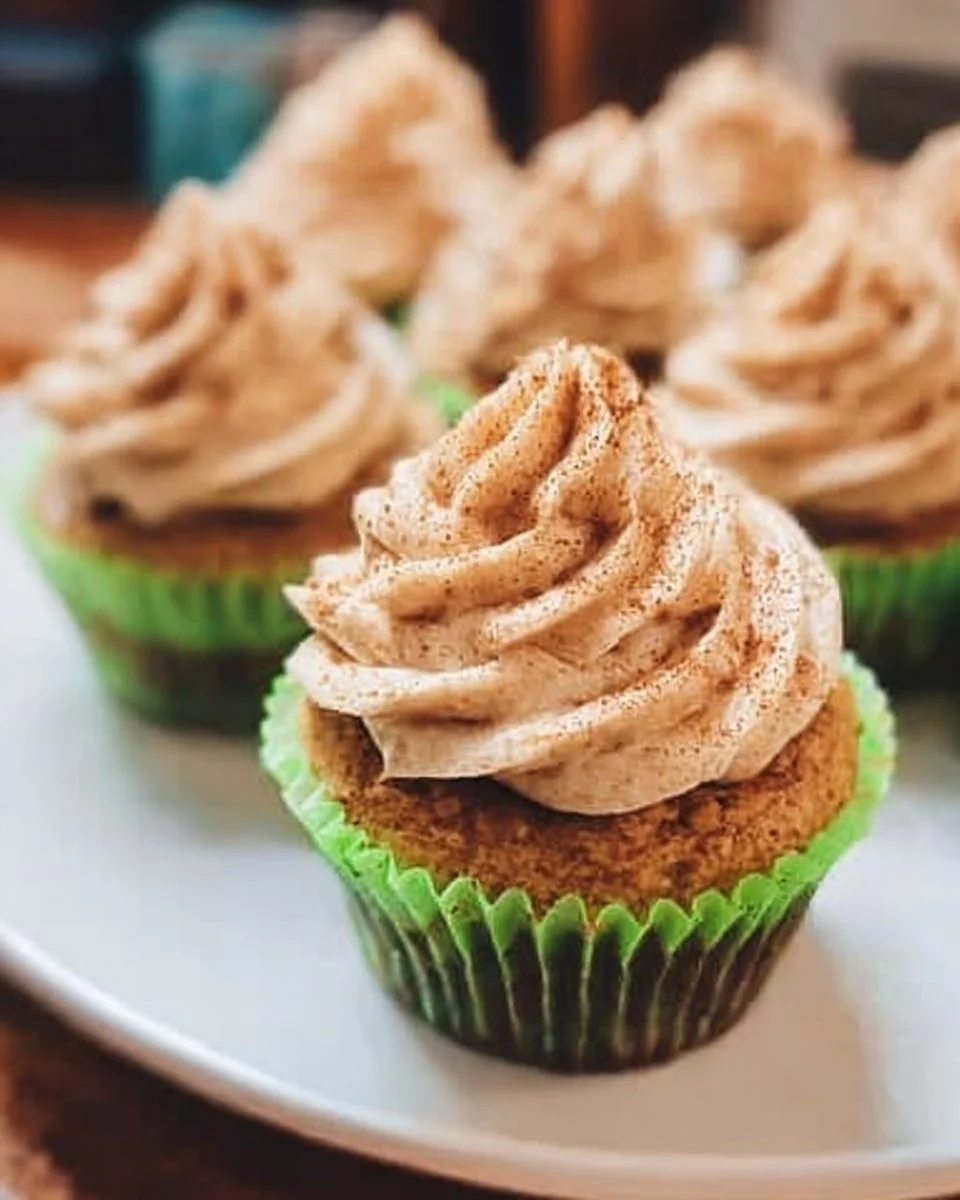 Spiced apple cupcakes with cinnamon icing on a rustic wooden table