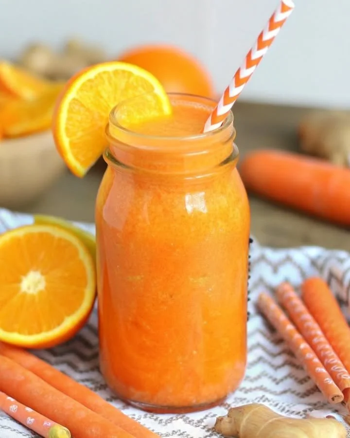 Orange Ginger Turmeric Smoothie in a glass with fresh ingredients around it