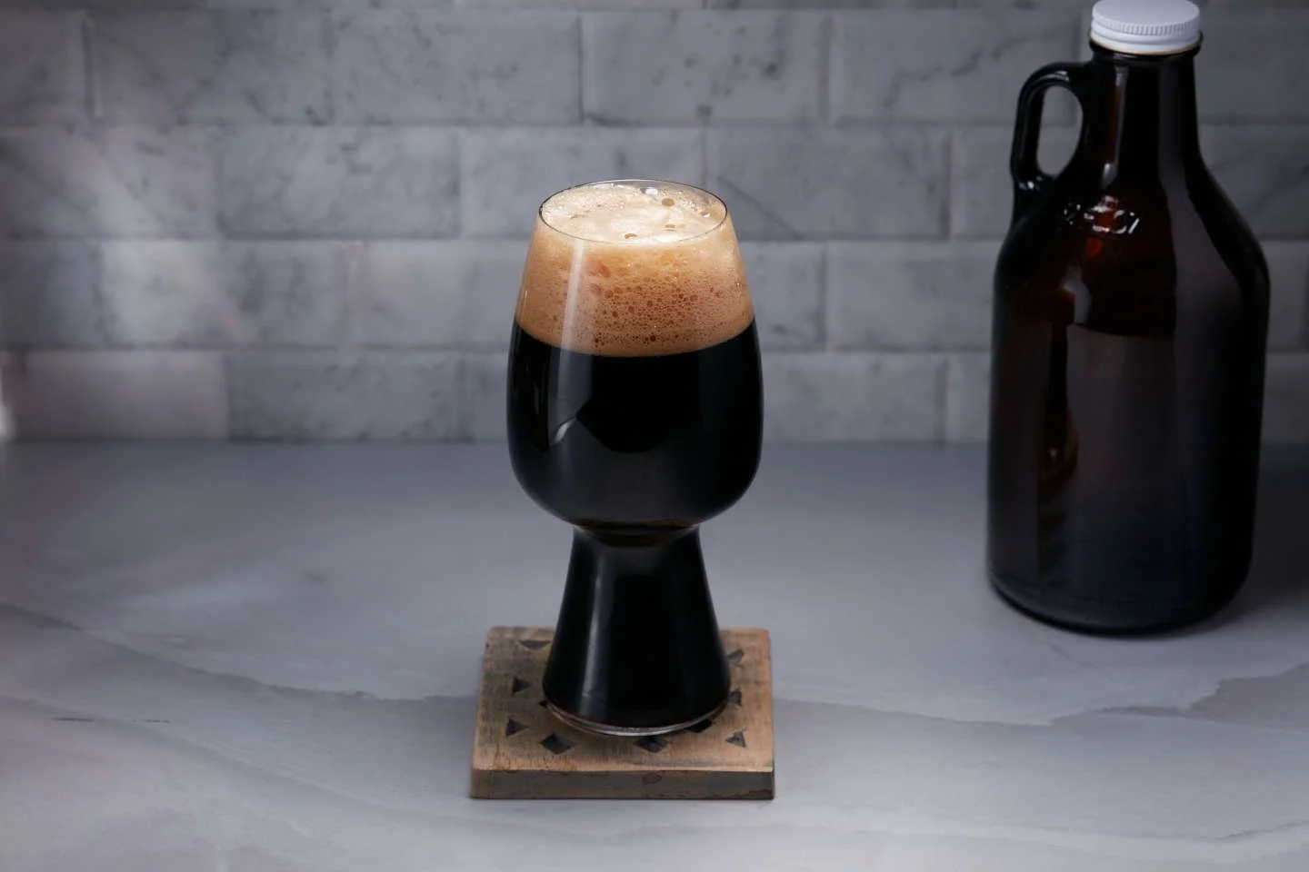 Pouring a glass of Slow Life Nitro Stout with creamy foam atop.