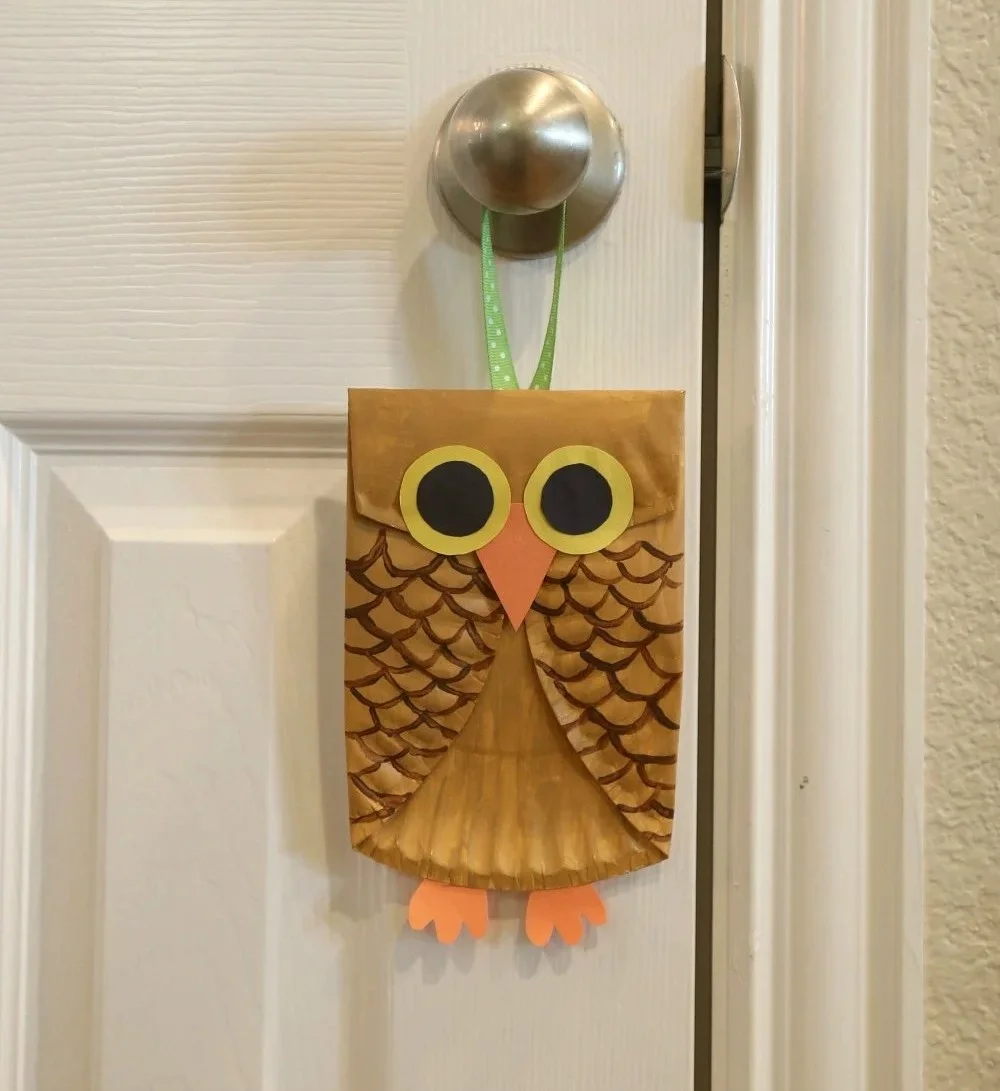 Kids smiling while creating a paper plate owl craft using colorful materials